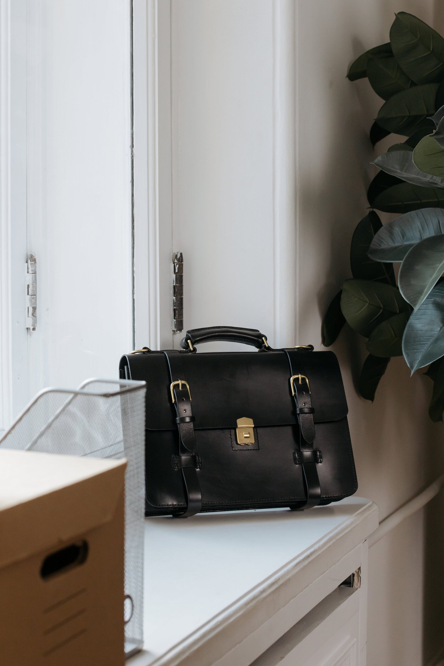 A picture of a leather flight bag on a window sill